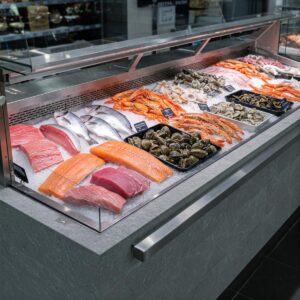 A modern, refrigerated display case showcasing various types of fresh fish, shrimp, and shellfish on ice.