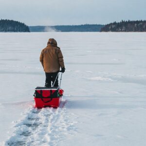  Illustration of a person pulling an empty ice fishing sled over a snow-covered ice surface.
