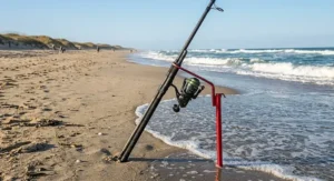 A 9 foot surf rod sitting in a beach sand spike holder waiting for a bite