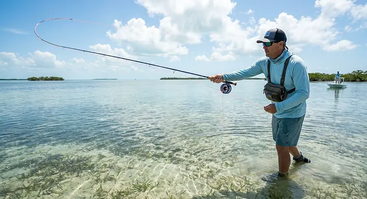 Angler casting an 8 weight fly rod for saltwater bonefish on a shallow ocean flat in Florida.