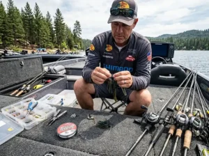 Angler rigging a bass jig with a 20lb fluorocarbon leader on the carpeted deck of a bass boat