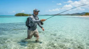 A fly fisherman wearing breathable fishing shorts for hot weather while wading through shallow coastal flats.