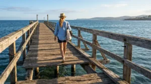 A fisherman in breathable fishing shorts for surf fishing walking along a wooden coastal pier.