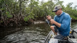 A heavy-duty inshore fishing combo bending as an angler fights a strong snook near mangrove roots.